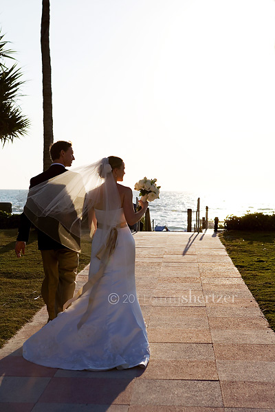 The bride and groom walk toward the beach after saying their vows.